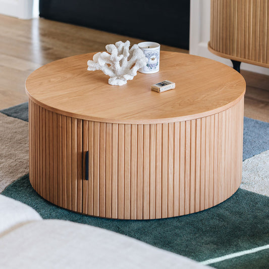 Round wooden coffee table Narural Wood with decorative items on a rug